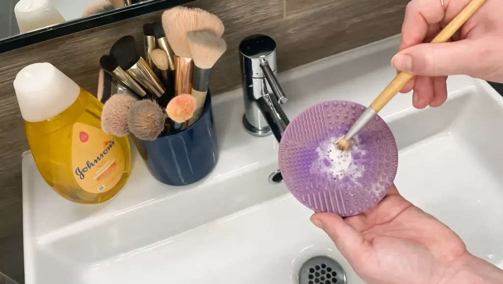 makeup brush cleaning setup with cleanser water bowl towel and silicone mat on bathroom vanity