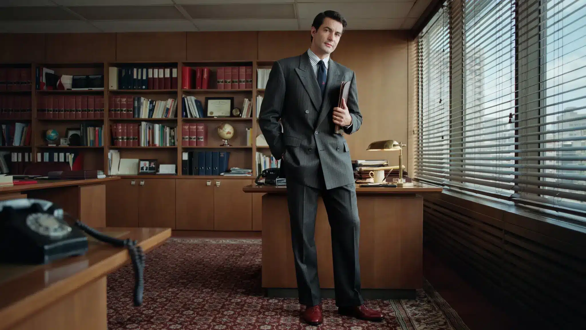 man wearing 80s power suit with double breasted jacket in vintage office setting