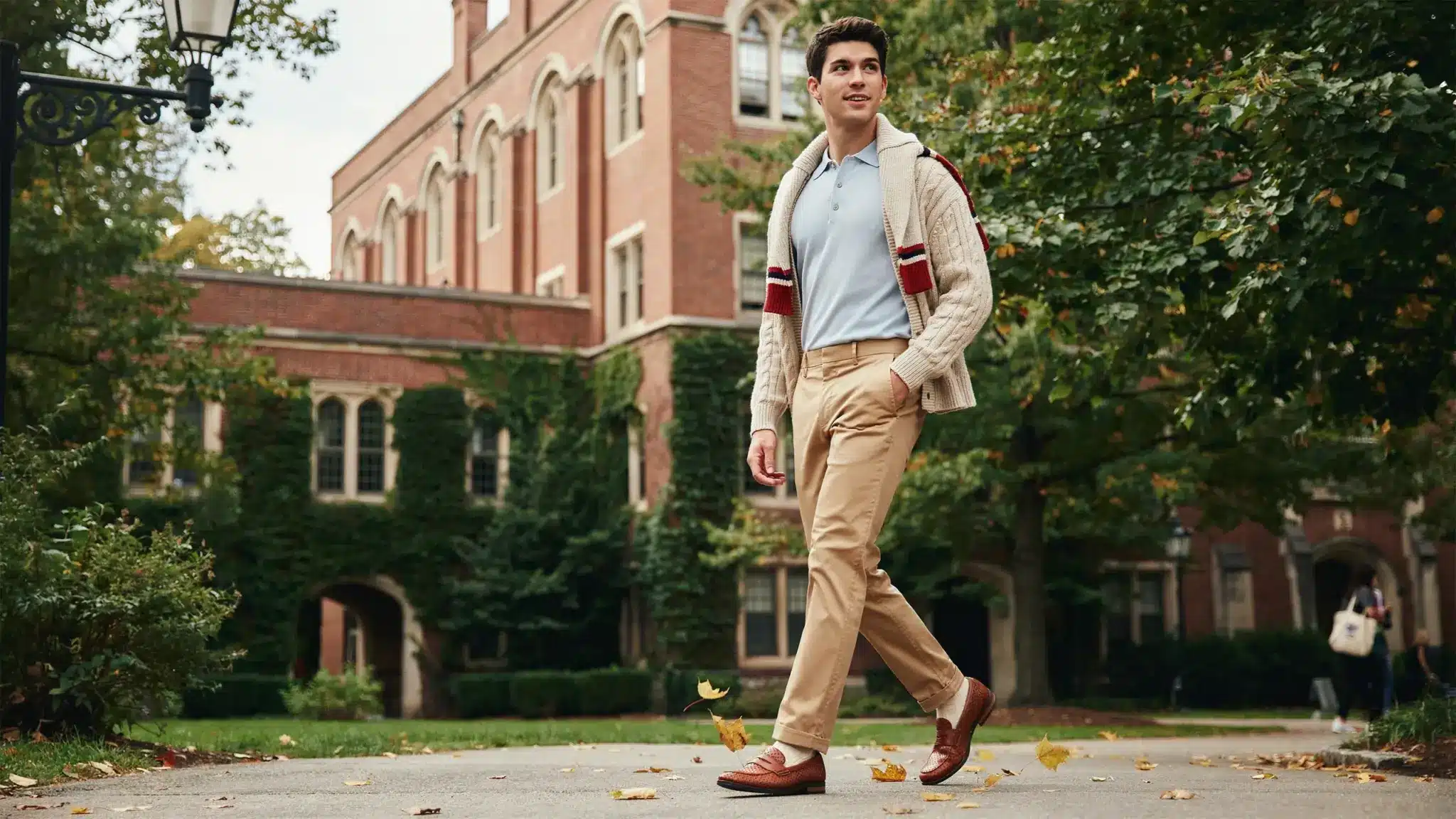 man wearing 80s preppy style with polo shirt chinos and sweater on college campus