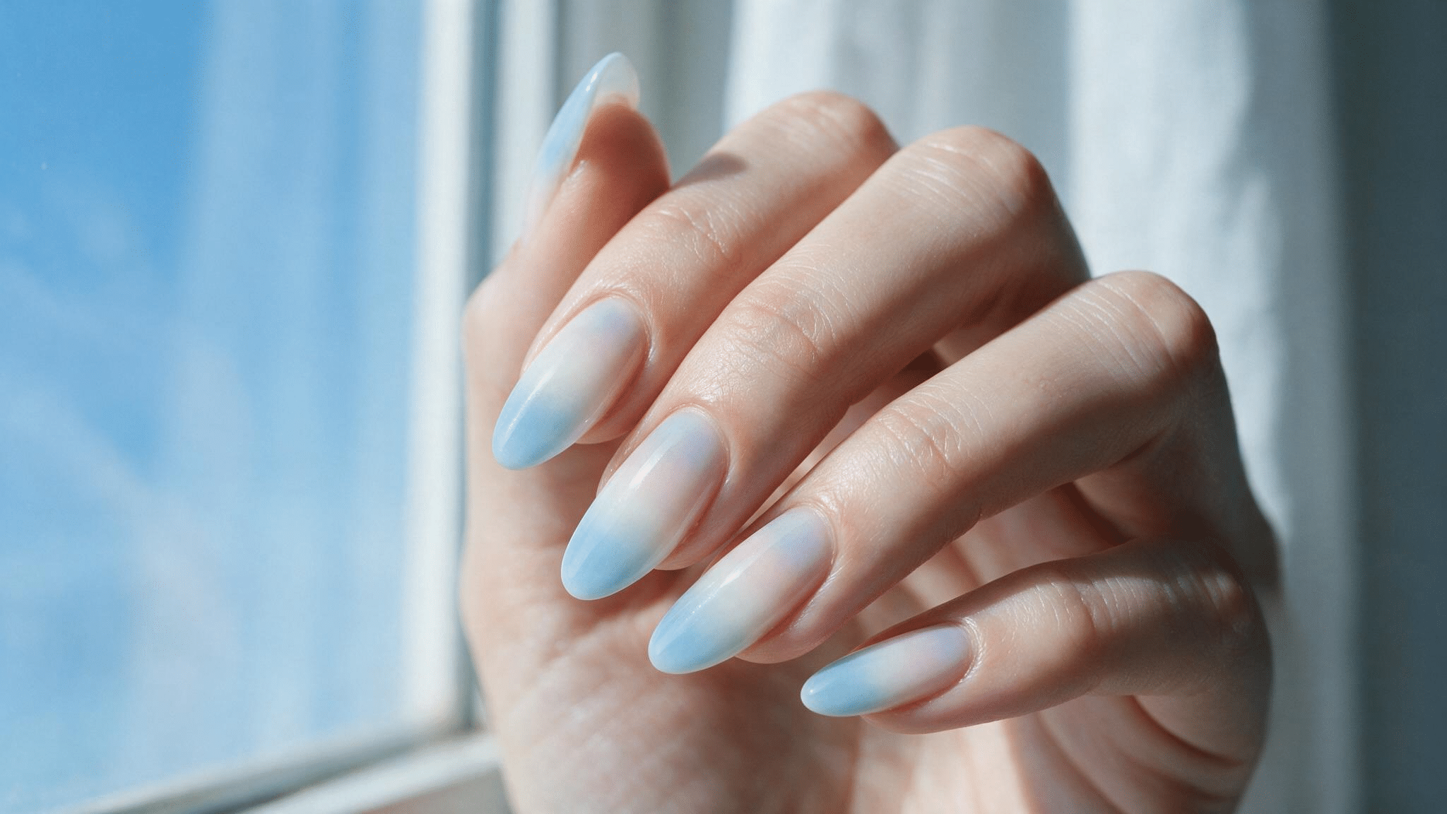 medium almond nails fading from powder blue to milky white and blush pink creating a soft early morning sky effect