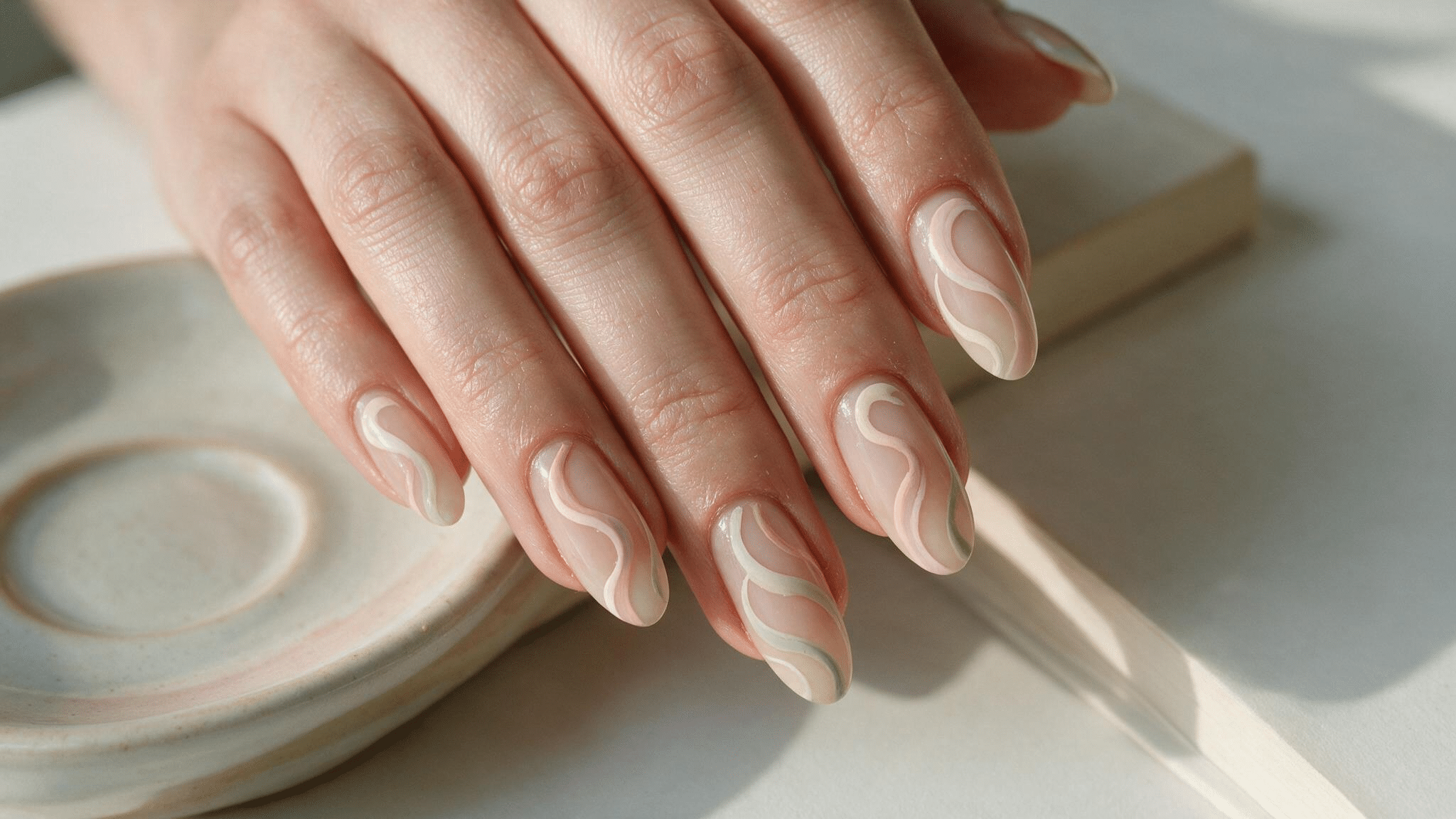 medium almond nails with blush ivory and sage swirls flowing across a translucent nude base with visible negative space