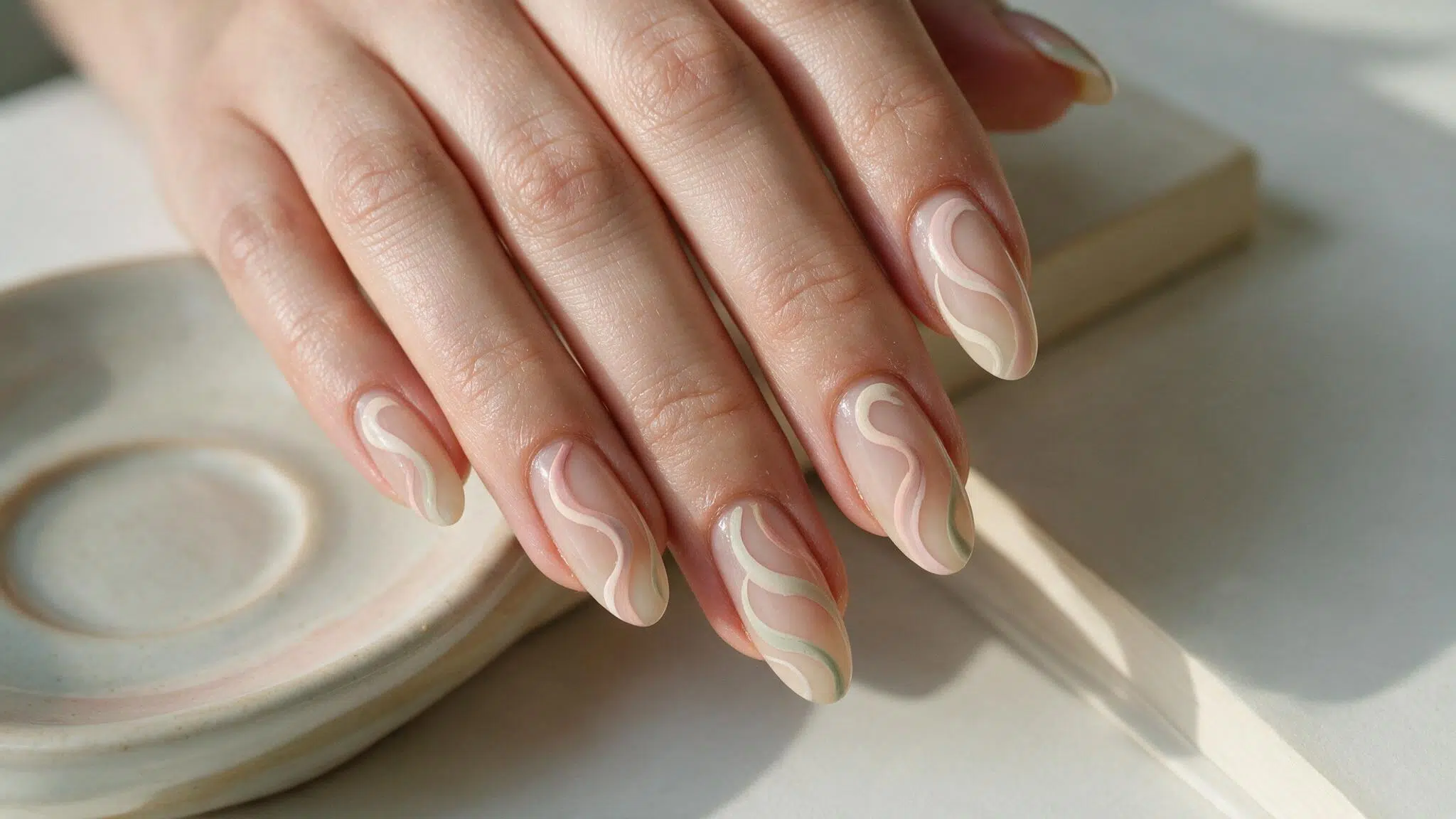 medium almond nails with blush ivory and sage swirls flowing across a translucent nude base with visible negative space