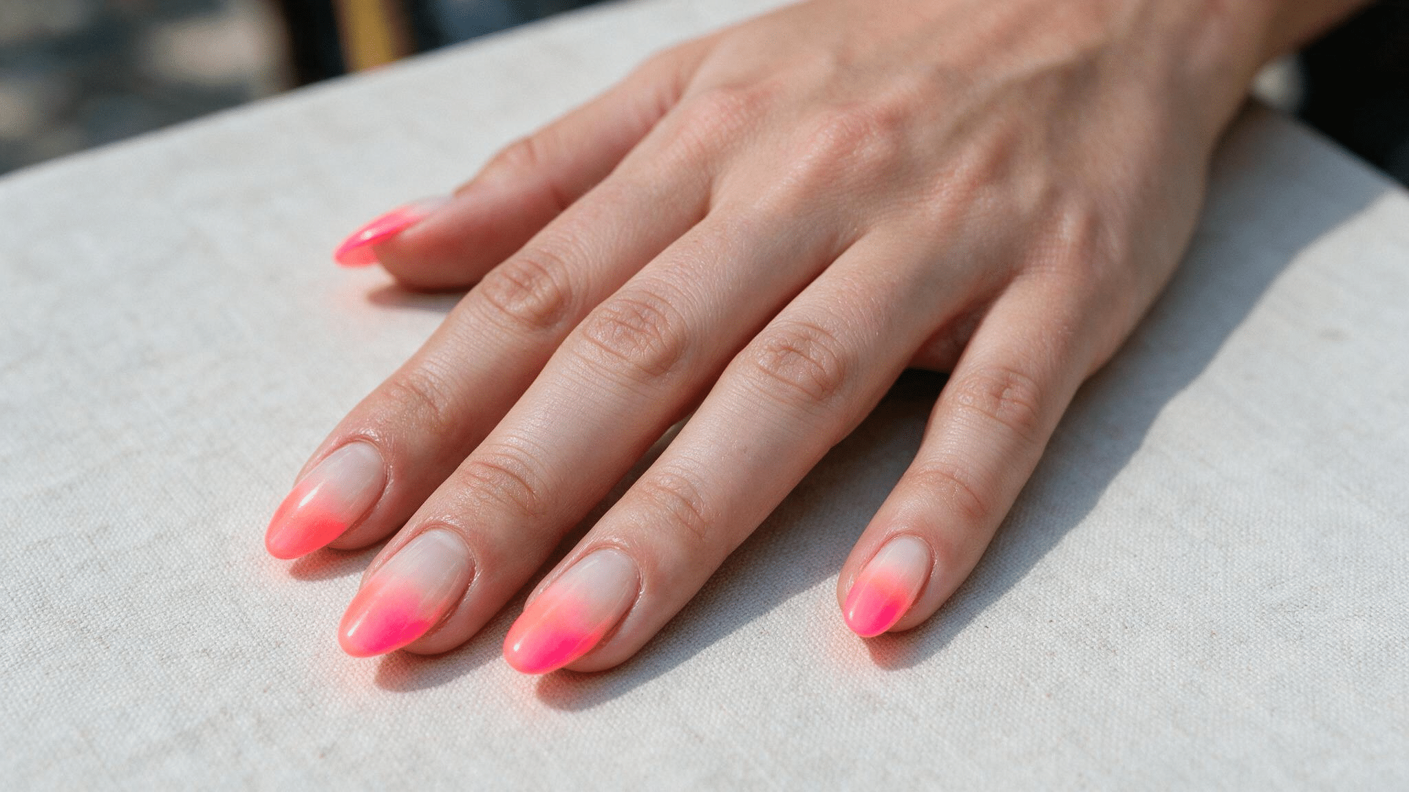 medium almond nails with coral neon fading softly into milky white creating a controlled bright spring ombre effect