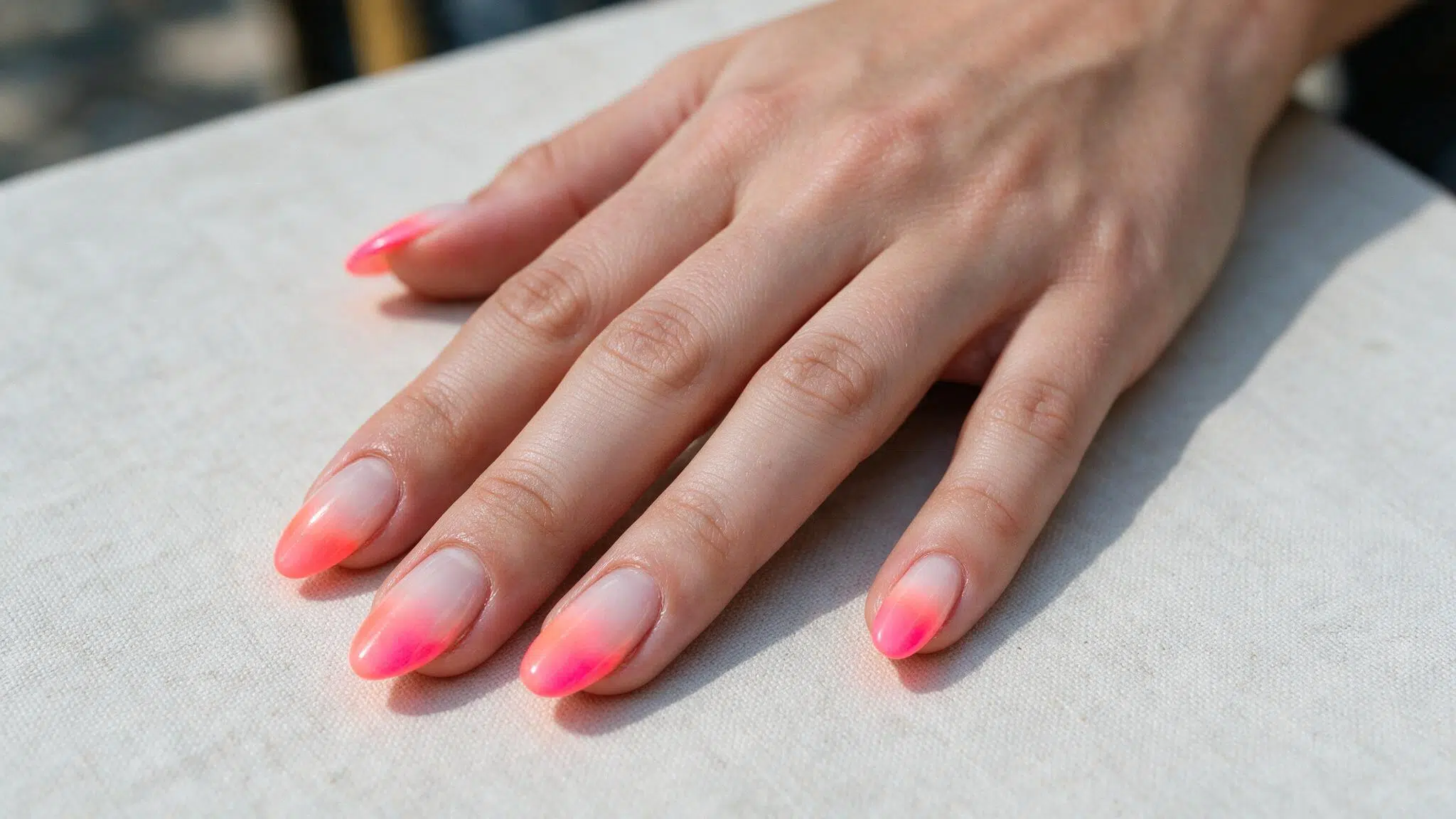 medium almond nails with coral neon fading softly into milky white creating a controlled bright spring ombre effect