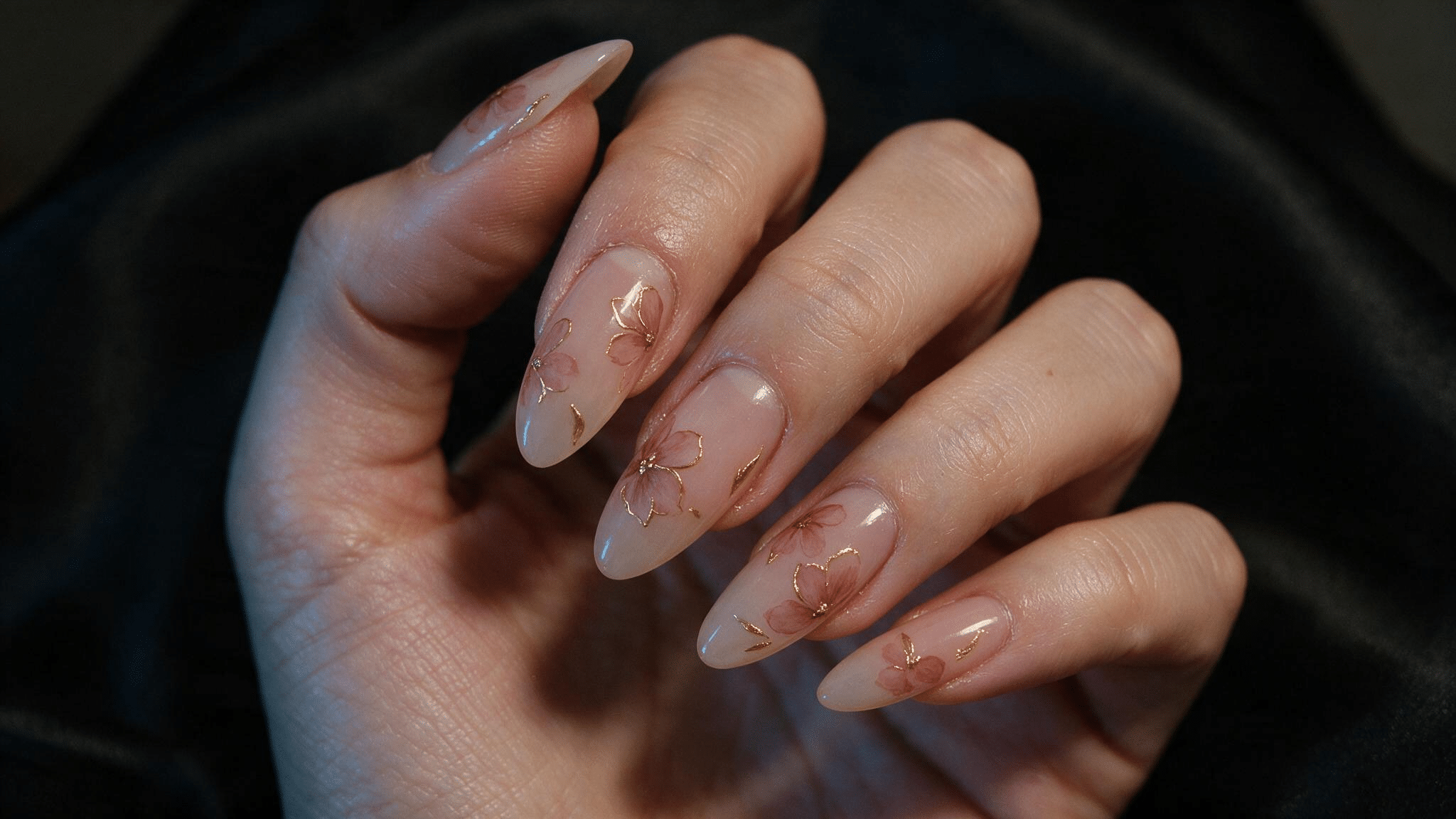 medium almond nails with soft pink flowers outlined in fine gold over a translucent blush base for a dressier spring look