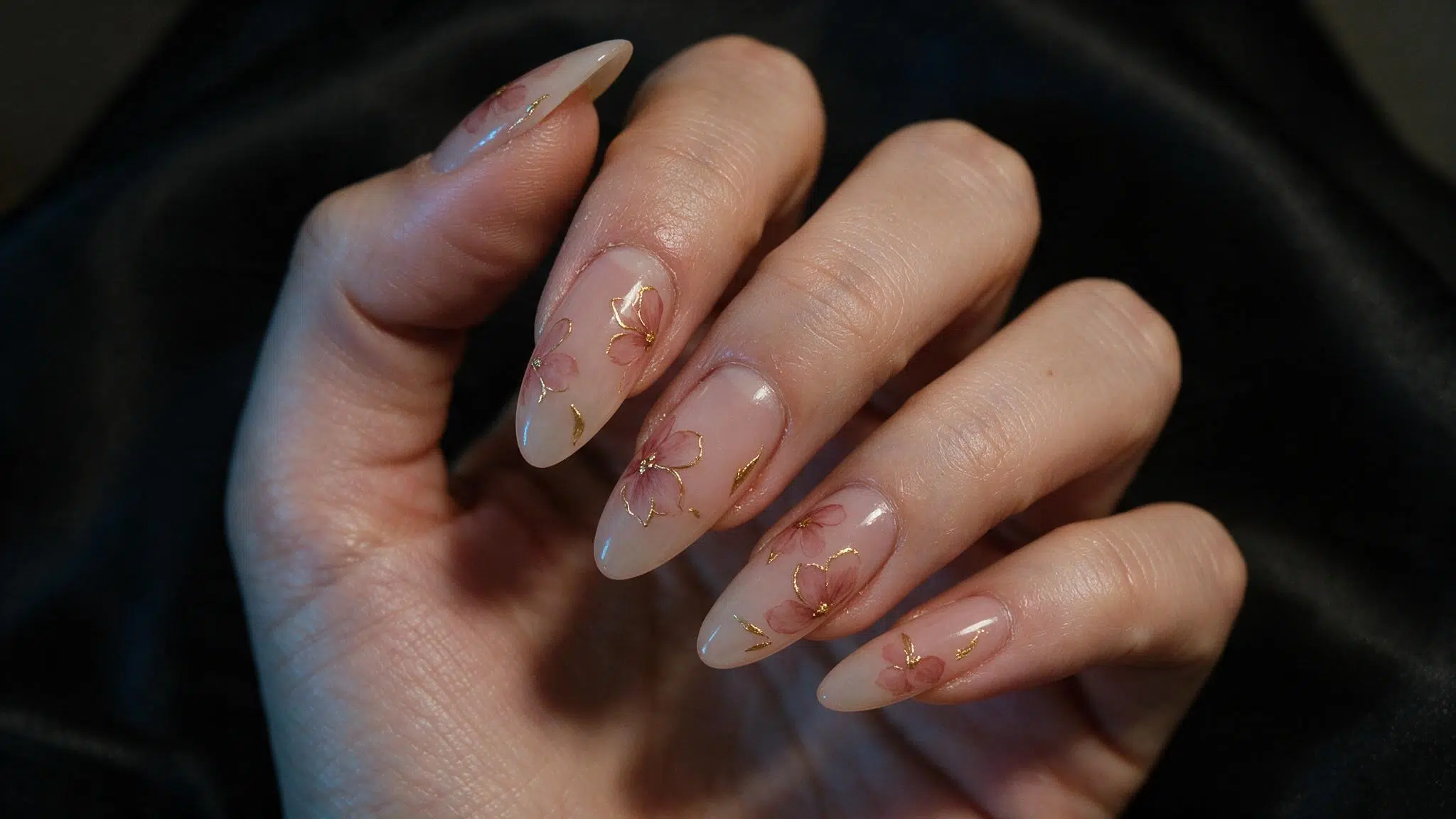 medium almond nails with soft pink flowers outlined in fine gold over a translucent blush base for a dressier spring look