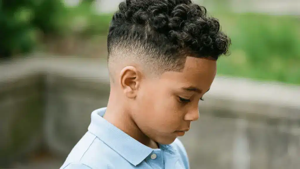 Mixed boy with a curly top and clean fade wearing a light blue polo in an outdoor park setting