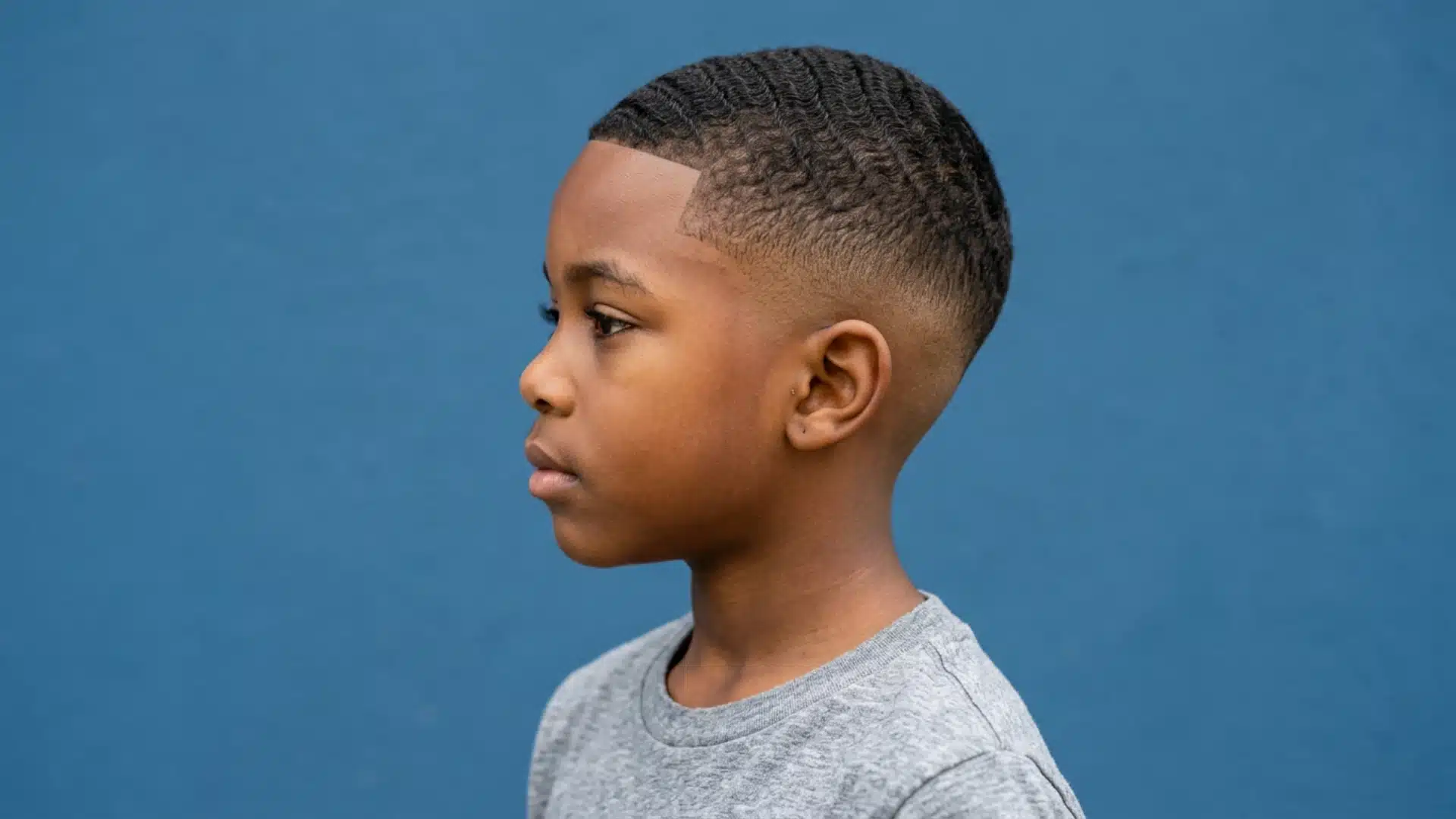 Mixed boy with a temple fade and natural curls kept full around the crown