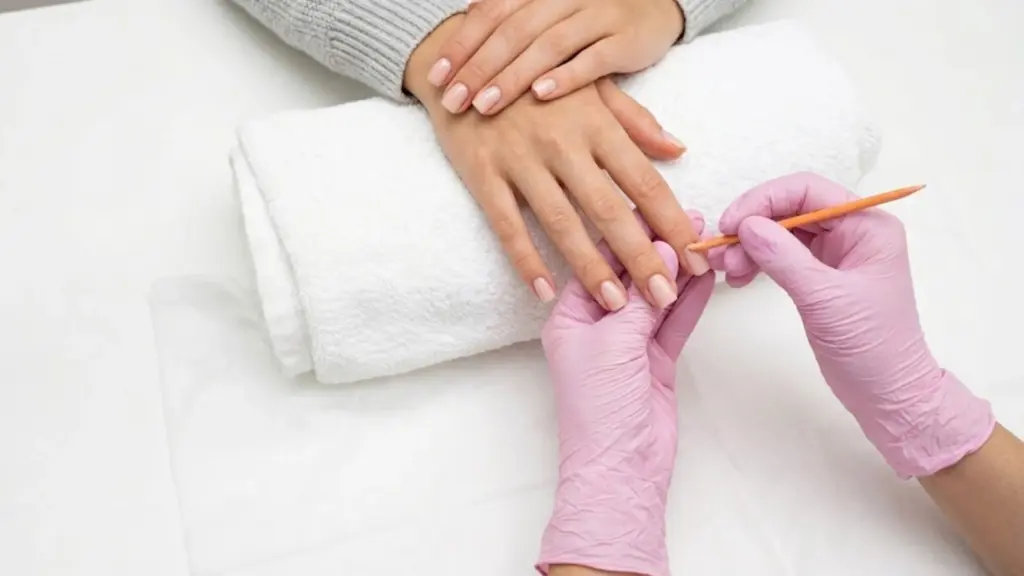 Professional nail technician performing a basic manicure with cuticle care on natural nails at a salon station