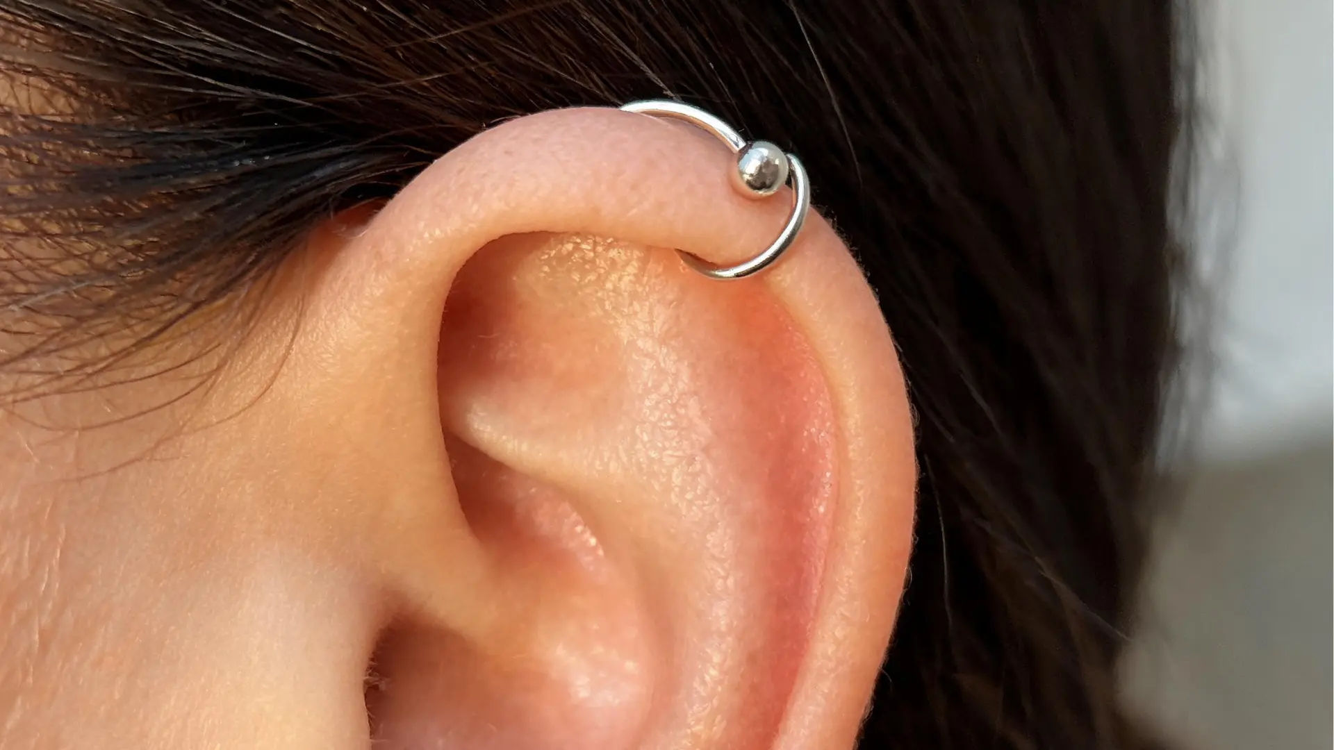 Silver hoop helix cartilage piercing