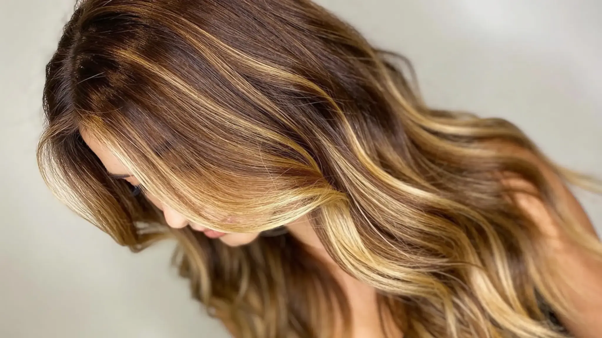 soft bronde balayage with warm brown and blonde highlights on long flowing textured hair