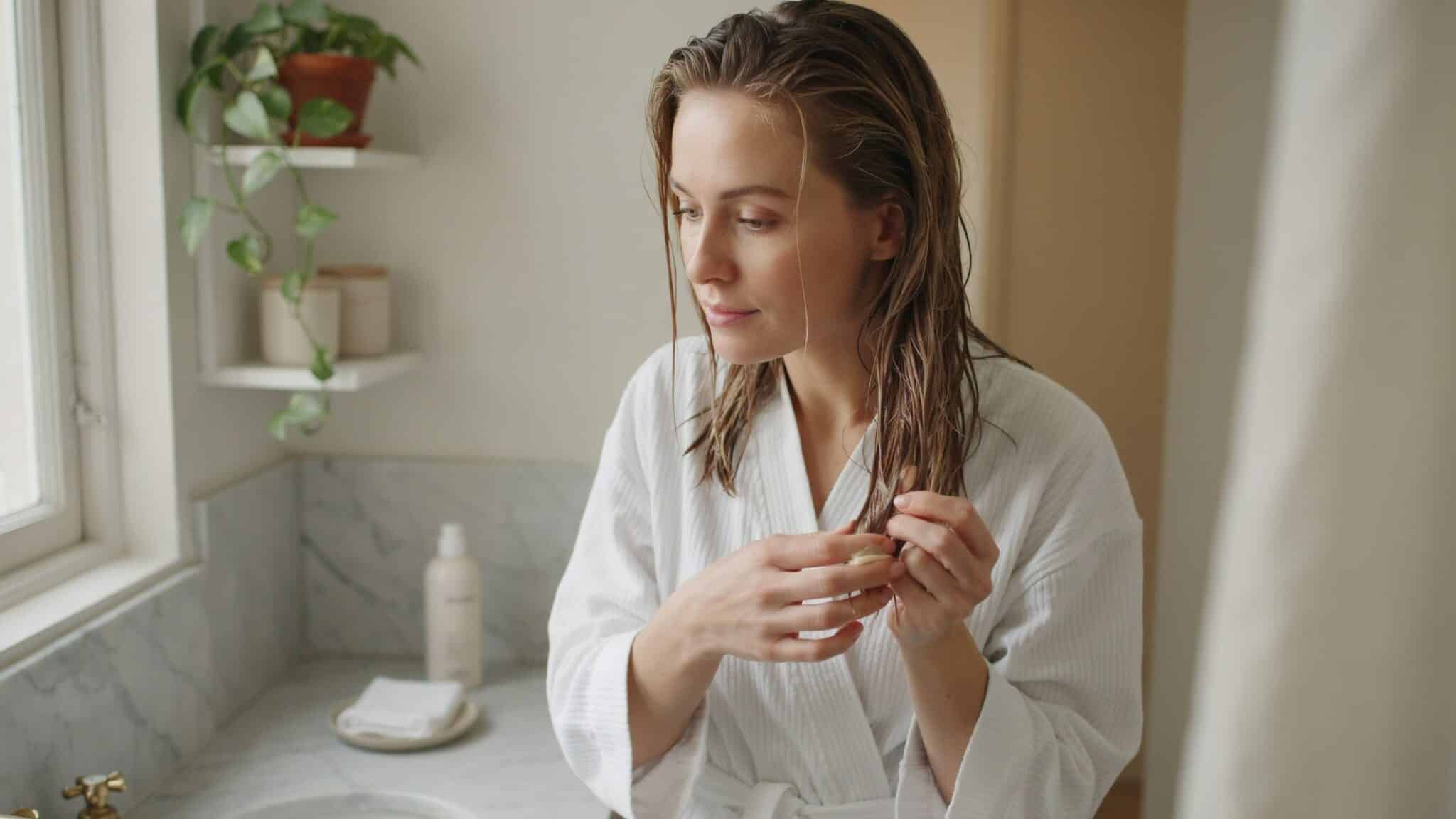 woman applying conditioner only to hair lengths in a bathroom shower