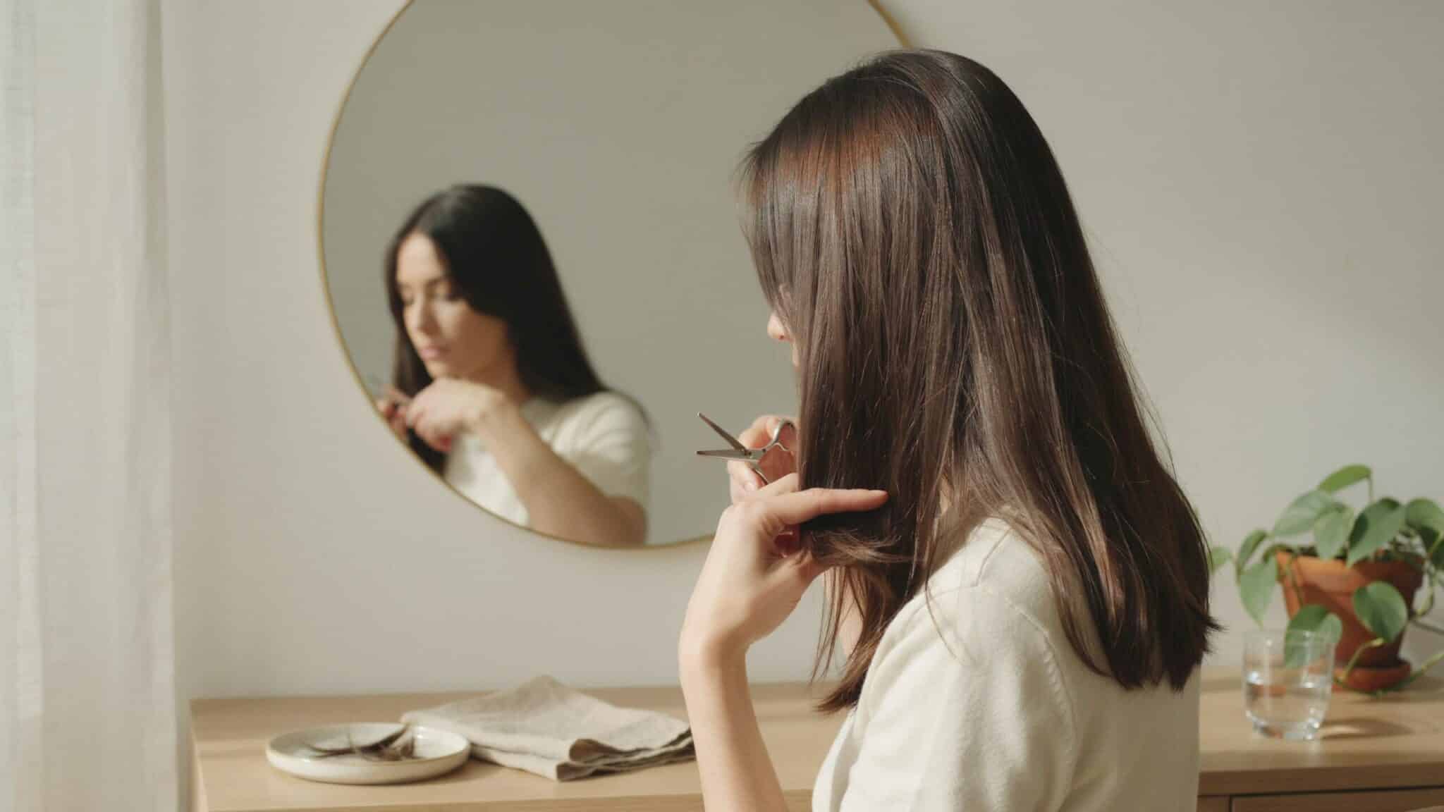 woman getting the ends of her hair trimmed to maintain a fuller hairstyle