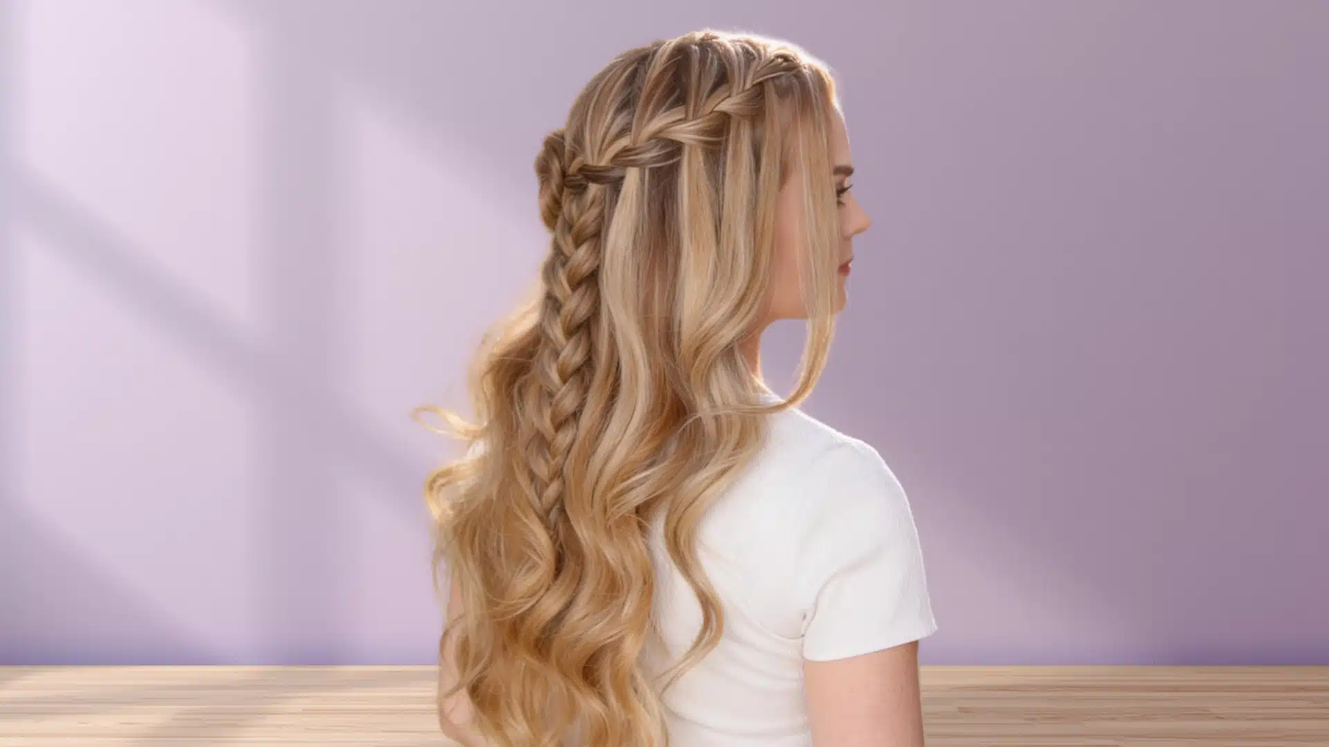 woman wearing waterfall braid half up hairstyle with cascading curls