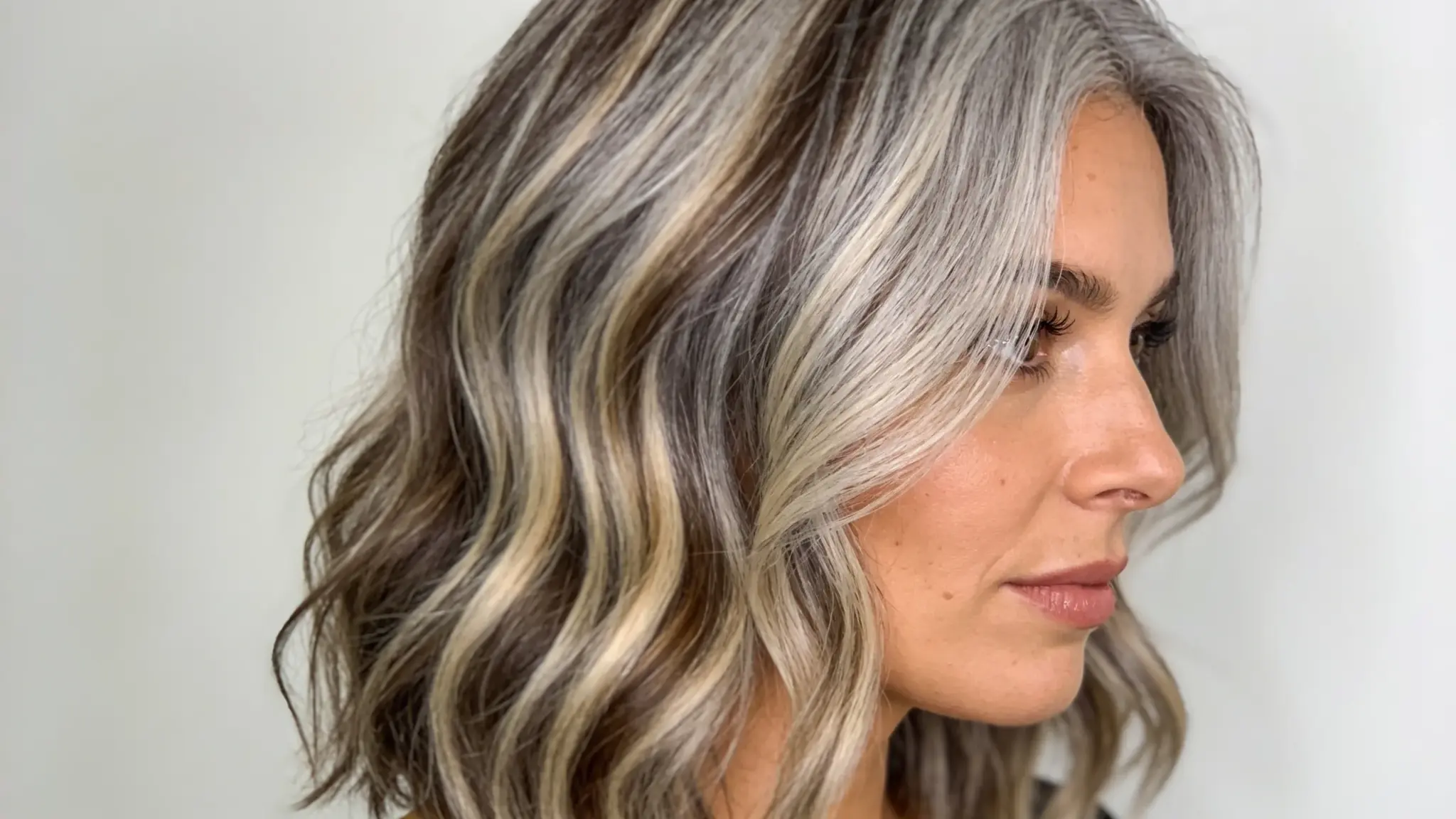woman with gray blending balayage featuring soft silver highlights and dimensional wavy hair