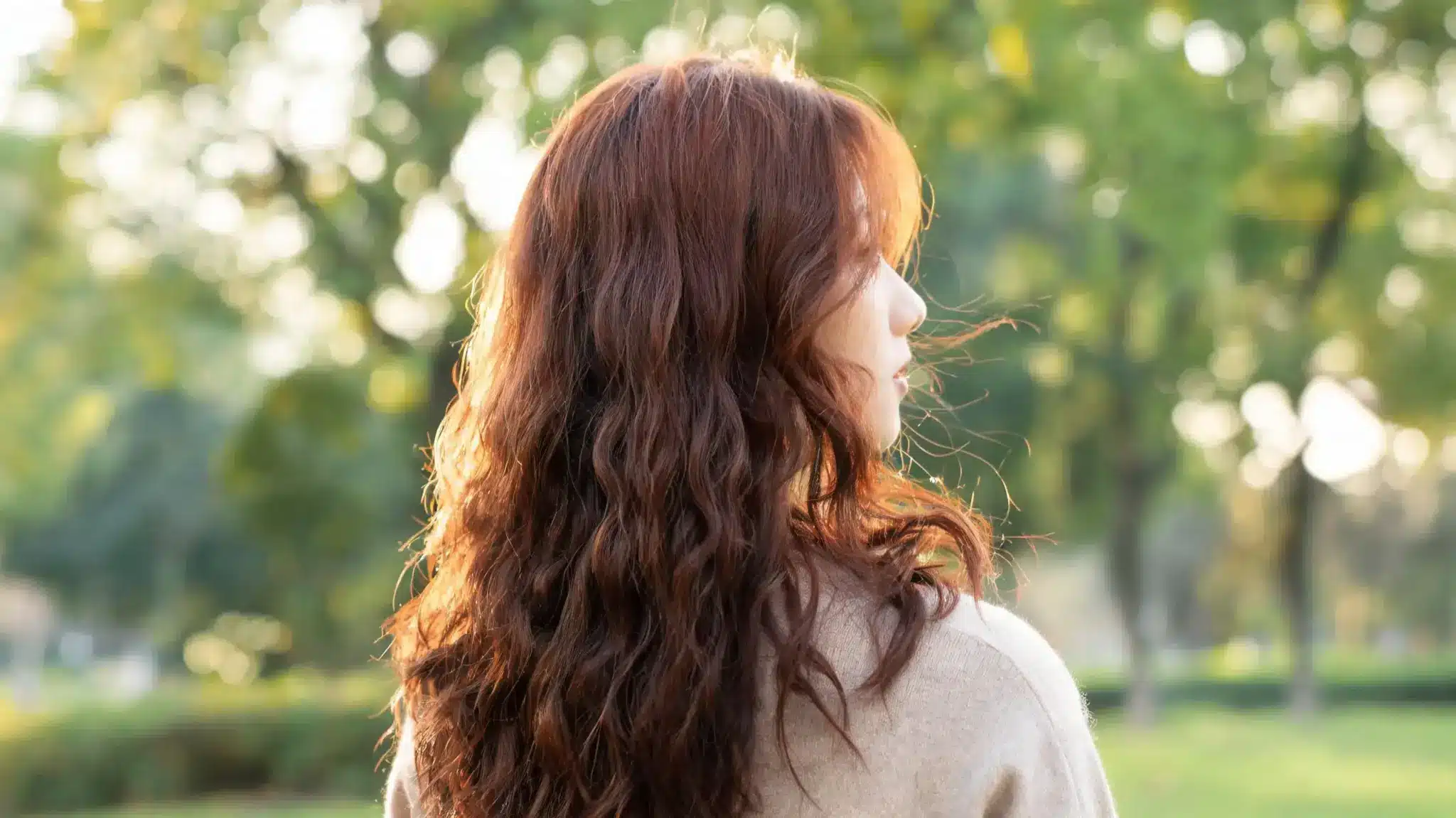 woman with natural irish curls showing soft waves and textured layered hair outdoors in sunlight