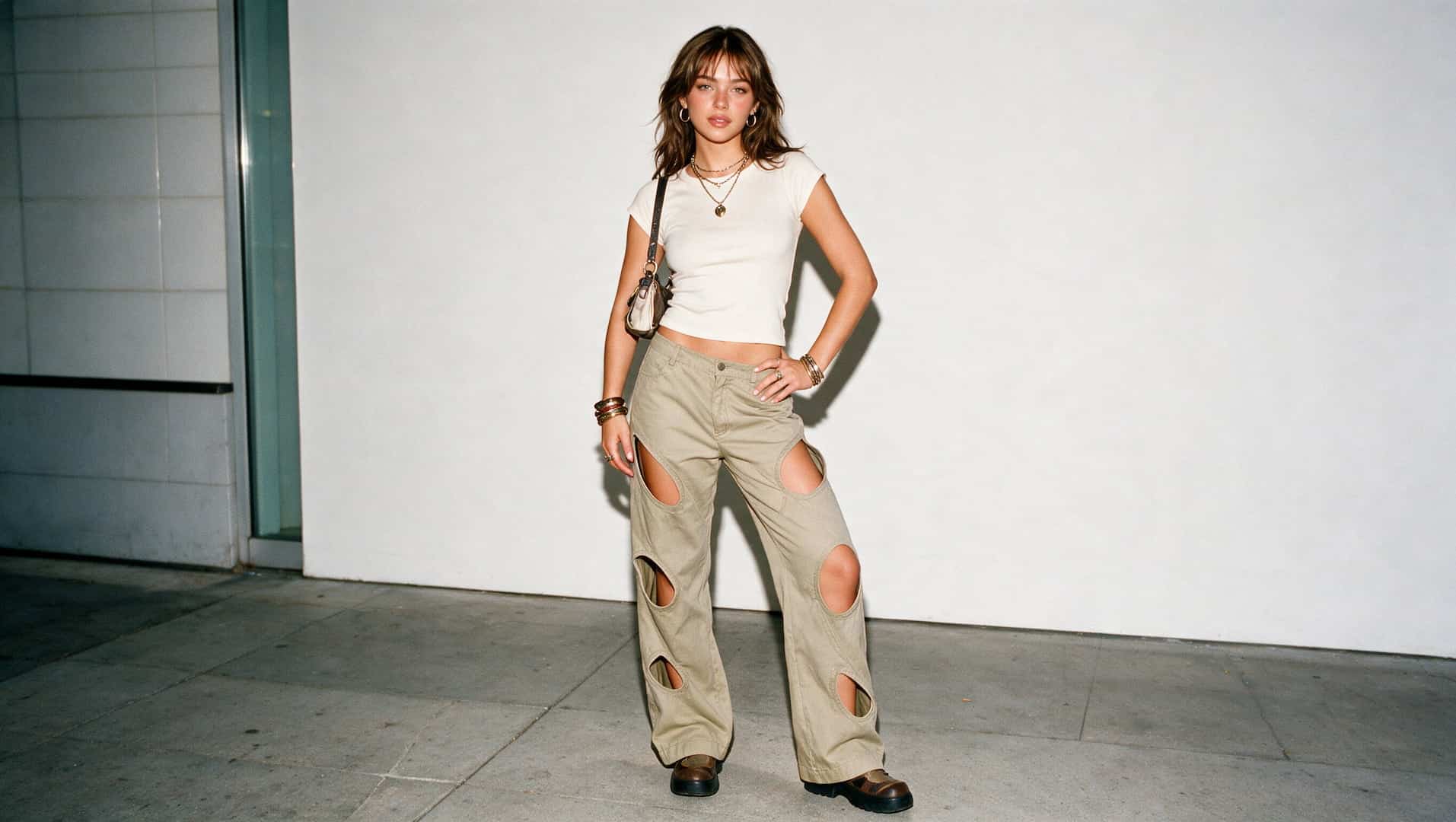 young woman in cut out pants and a fitted top with a mini bag and chunky shoes in a y2k look