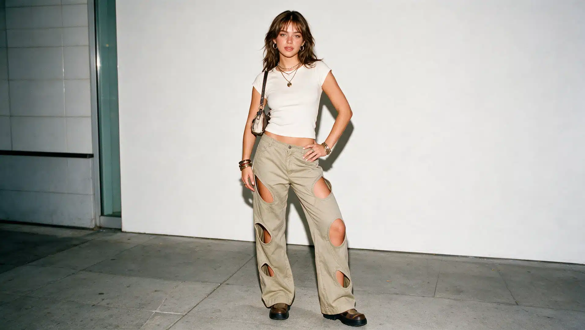 young woman in cut out pants and a fitted top with a mini bag and chunky shoes in a y2k look