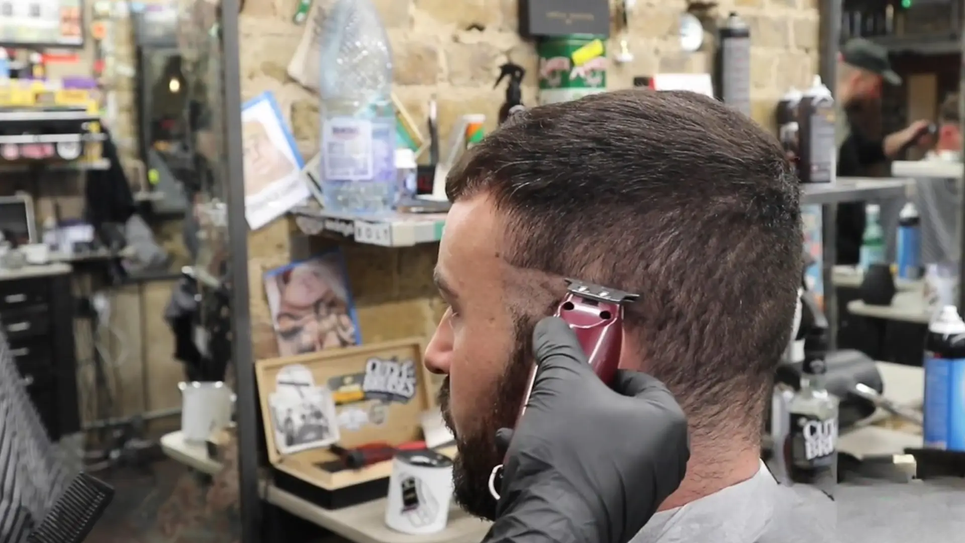 YouTube video showing barber using clipper for fade haircut with tutorial and related haircut videos on screen
