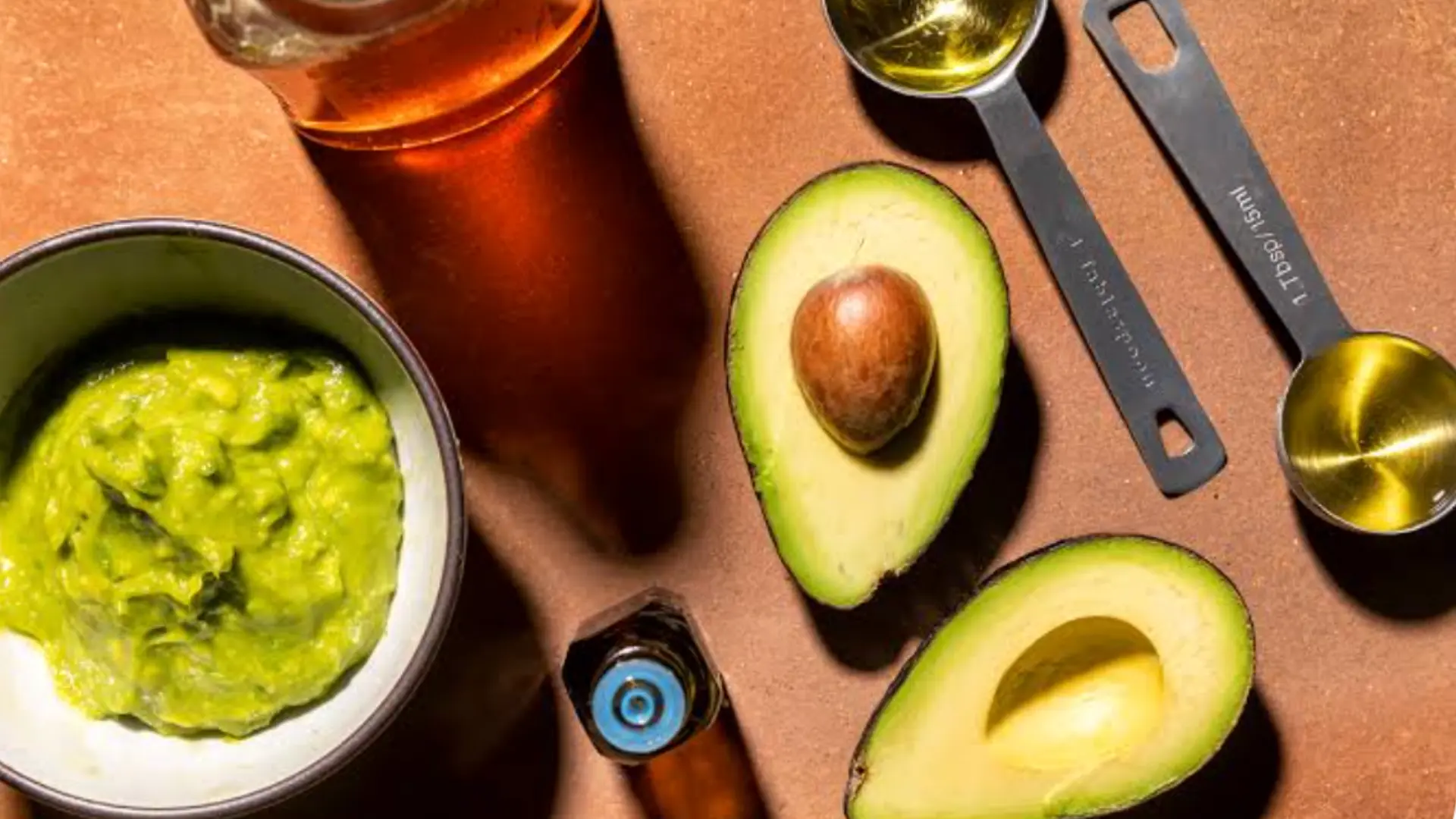 ripe mashed avocado inside a clear glass bowl drizzled with thick, golden raw honey from a jar