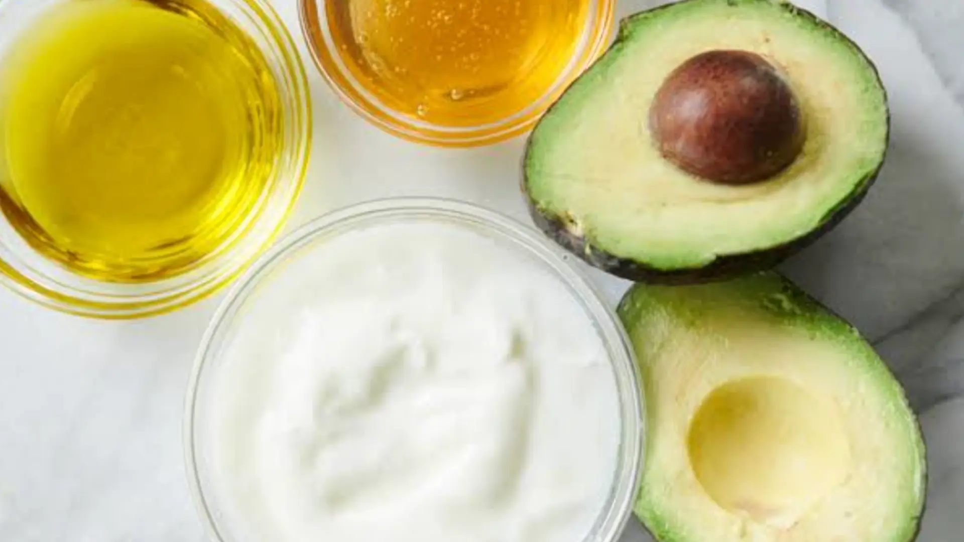 creamy white yogurt swirling together with bright green mashed avocado inside a rustic wooden bowl with a spoon