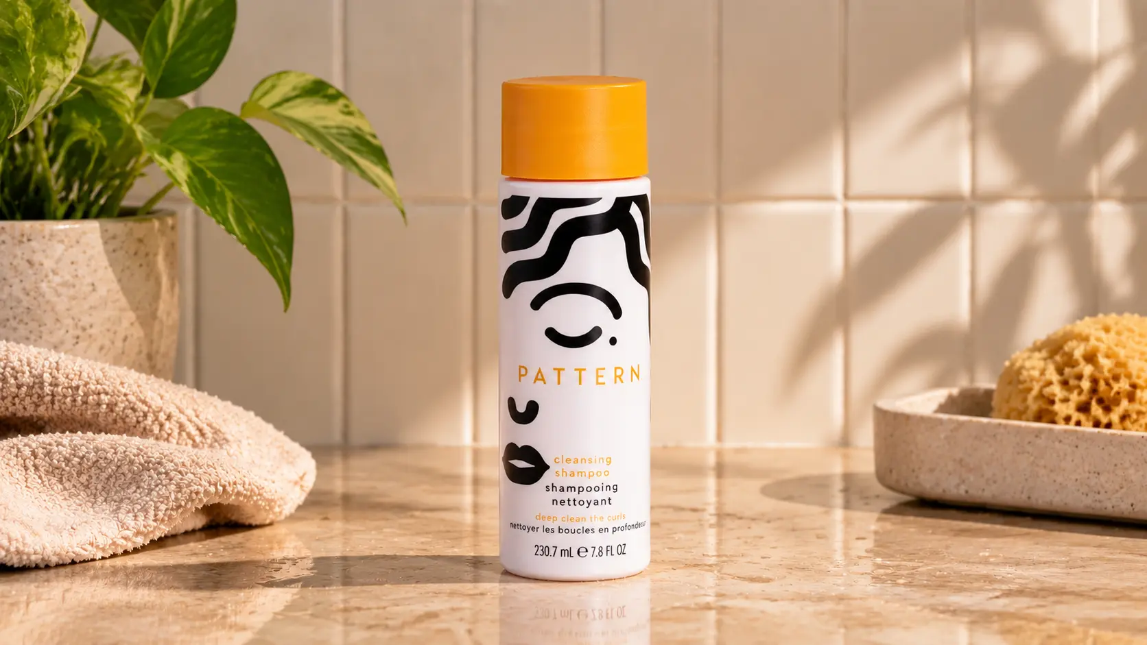 pattern shampoo bottle displayed cleanly on a bathroom counter with towel plant and sponge nearby